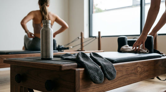 Close-up of worn grip socks resting on a Pilates reformer carriage in a quiet studio.