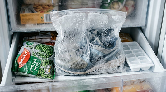 A pair of running shoes inside a plastic bag in a kitchen freezer next to frozen food, highlighting the freezing shoes to kill bacteria myth.