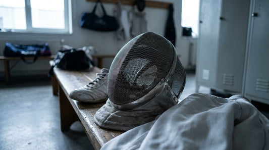 A discarded fencing mask and a single white fencing shoe on a gym bench, evoking the smell of athletic gear.