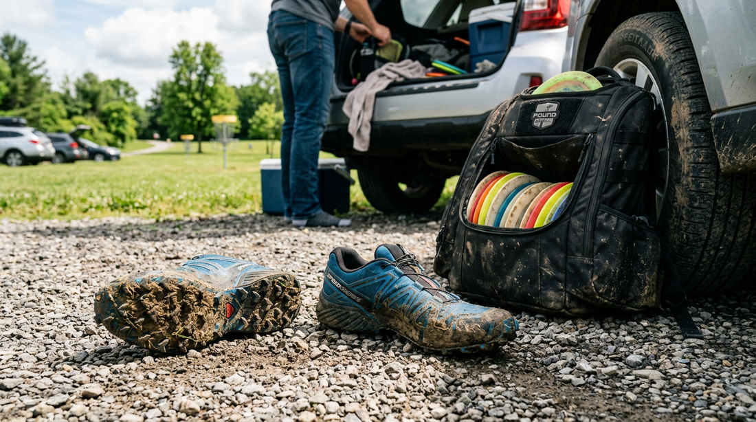 Muddy disc golf shoes and a professional disc golf bag sitting by an open car trunk after a round.