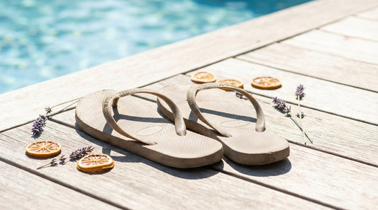 A pair of colorful rubber flip flops resting on a sun-drenched wooden deck near a swimming pool, evoking a hot summer day.