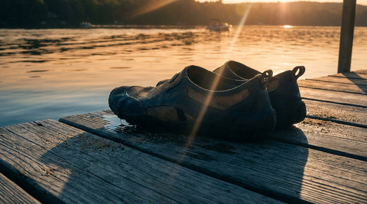 Wet, sandy water shoes abandoned on a sun-bleached wooden dock at sunset, illustrating how trapped moisture leads to odor.